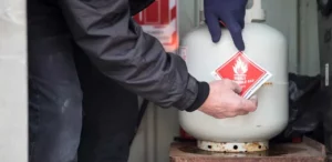 Man putting a Class 2 Flammable Gas sticker on a small gas cylinder